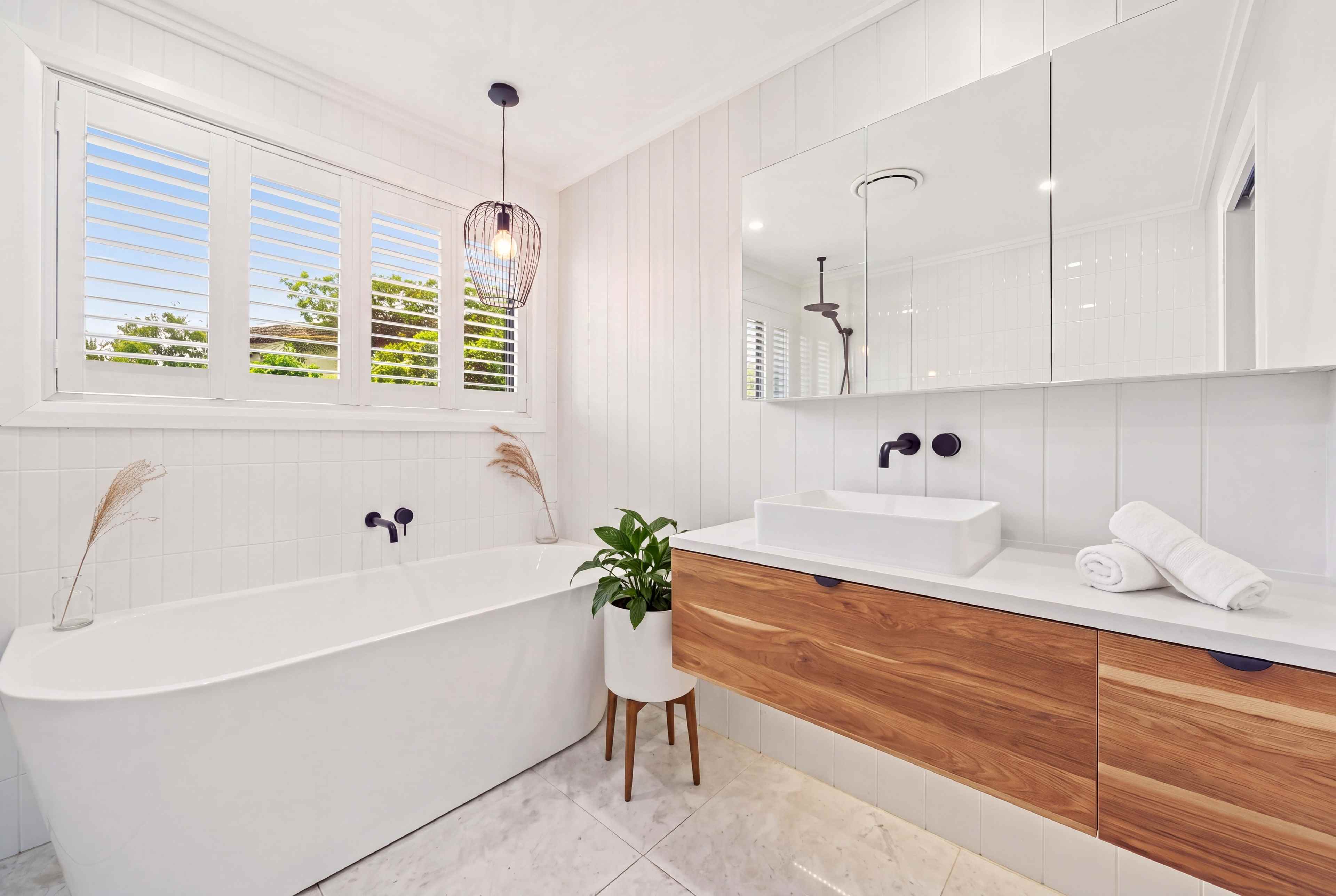 Bathroom with a freestanding bath, plantation shutters and an oak vanity
