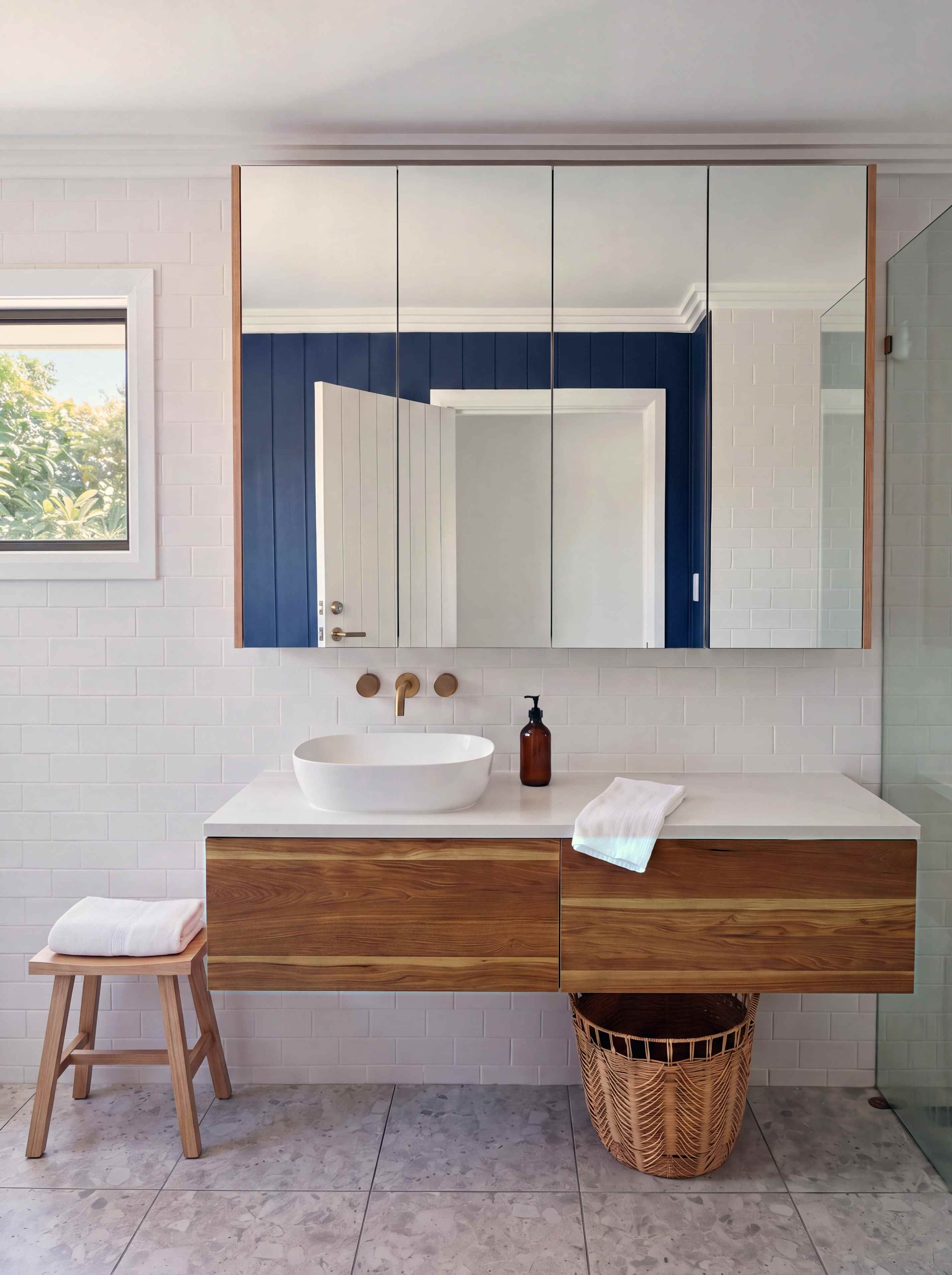 Floating timber vanity with a stone top, a vessel basin and brushed brass tapware under a mirrored cabinet