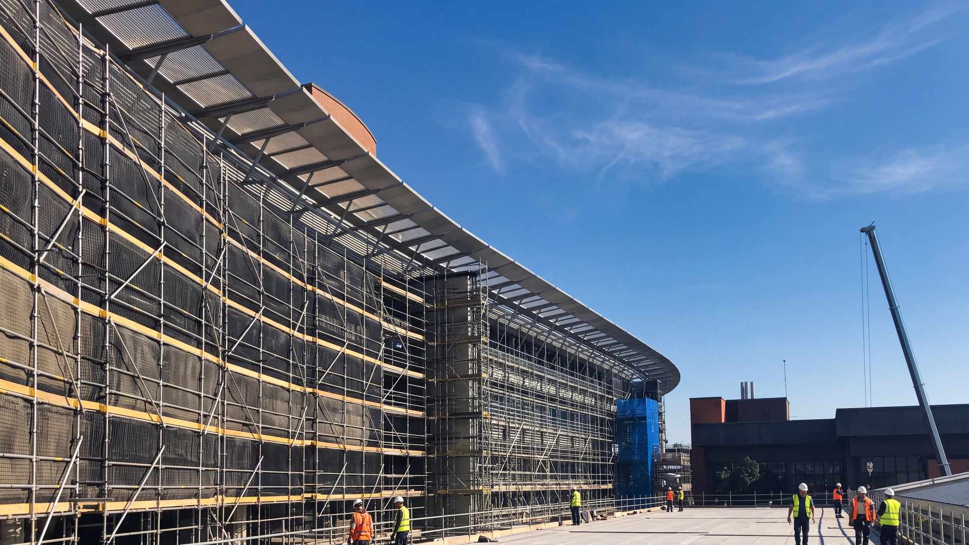 The sweeping curved canopy of a large public building wrapped in scaffold during its refurbishment