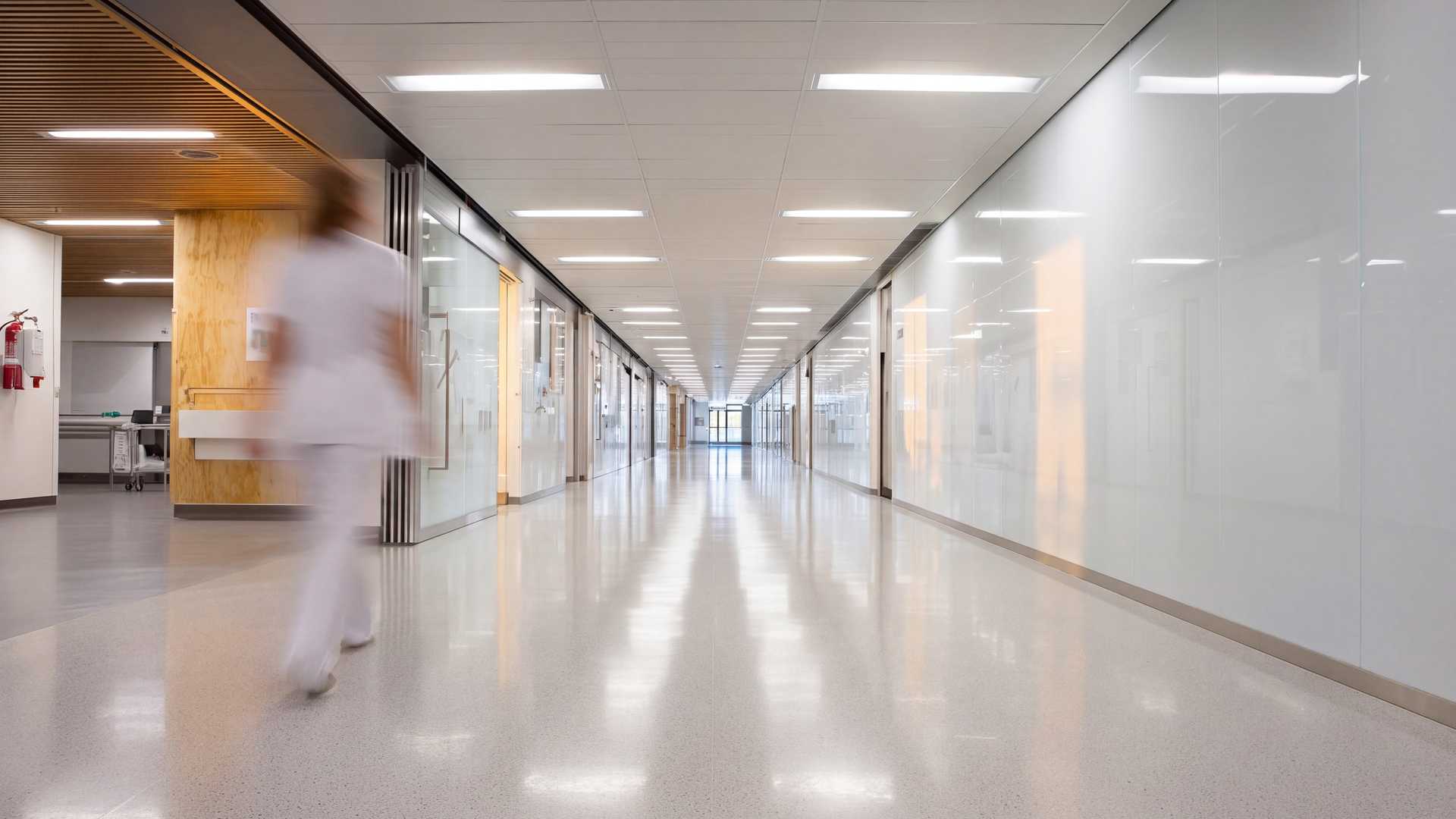 A nurse walks along a bright, newly finished hospital corridor