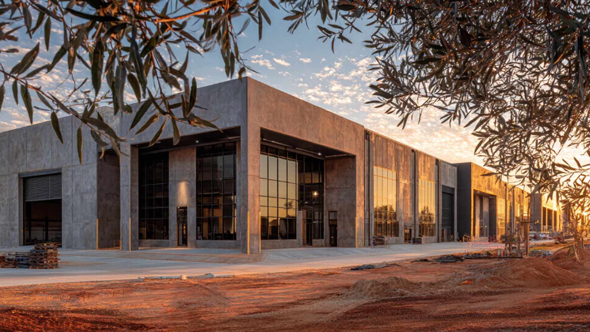 A new precast concrete industrial facility at sunset, framed by gum trees