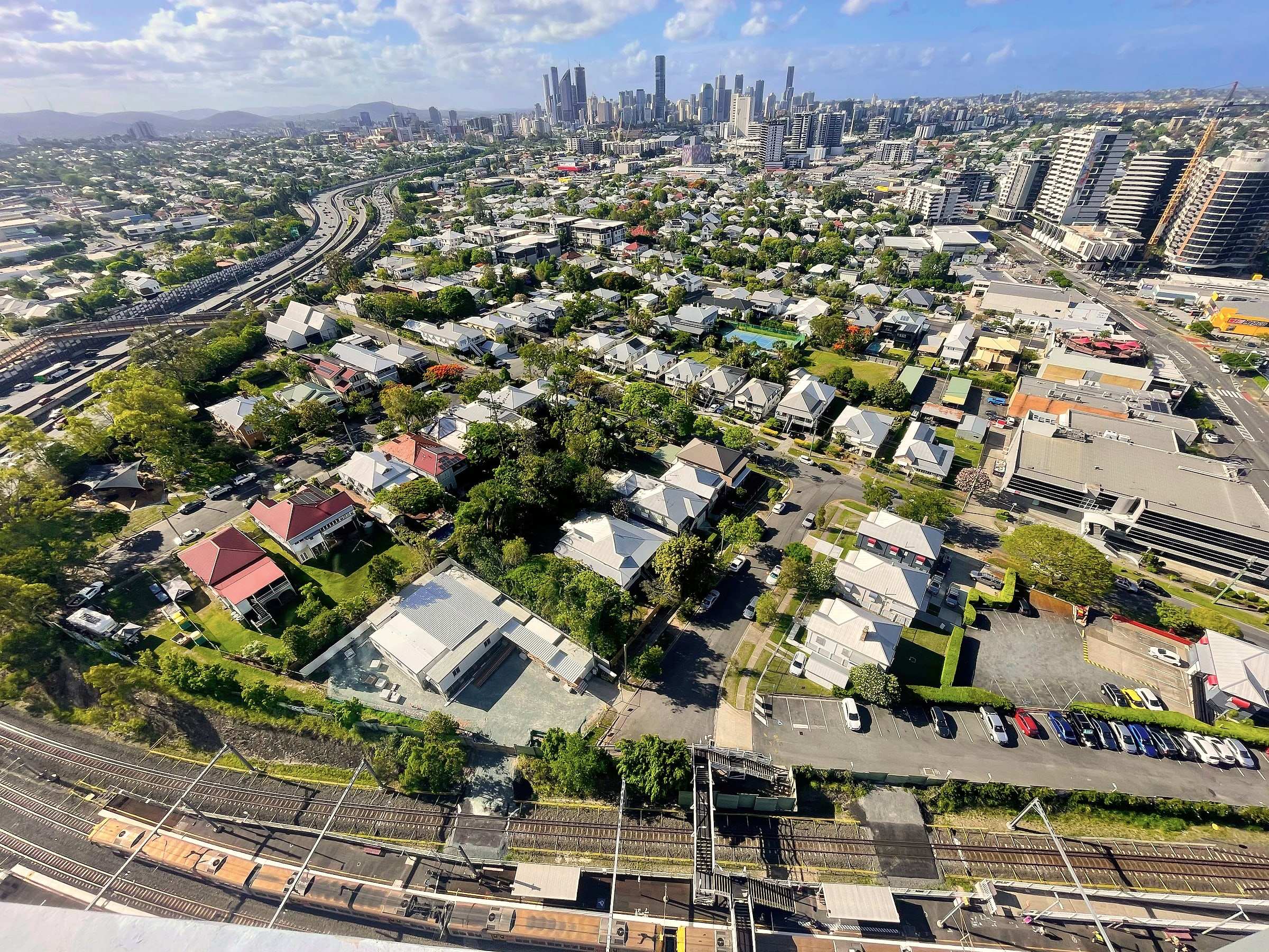Looking along a rail corridor from the air towards the Brisbane city skyline