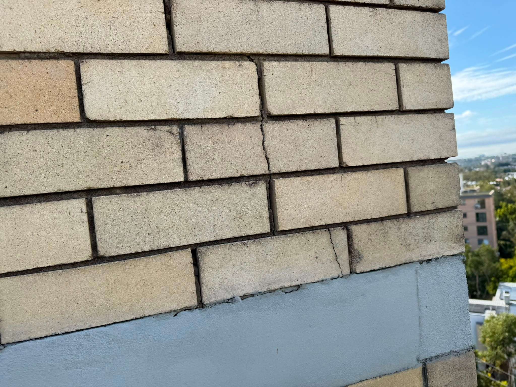 Cream face brickwork at a corner of the St Lucia tower, above a painted slab edge