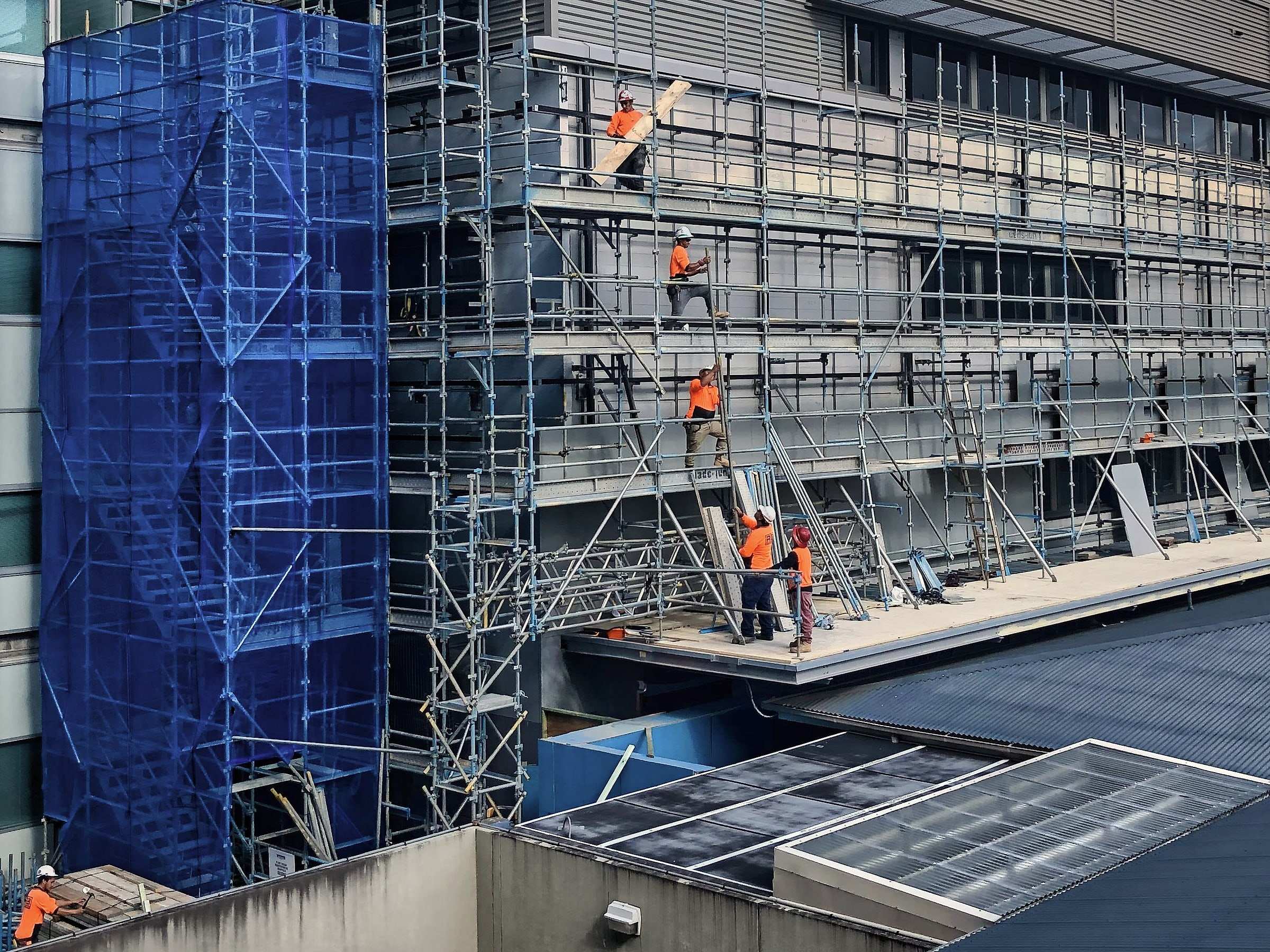 A crew in hi-vis installing cladding from scaffold on a multi-storey building