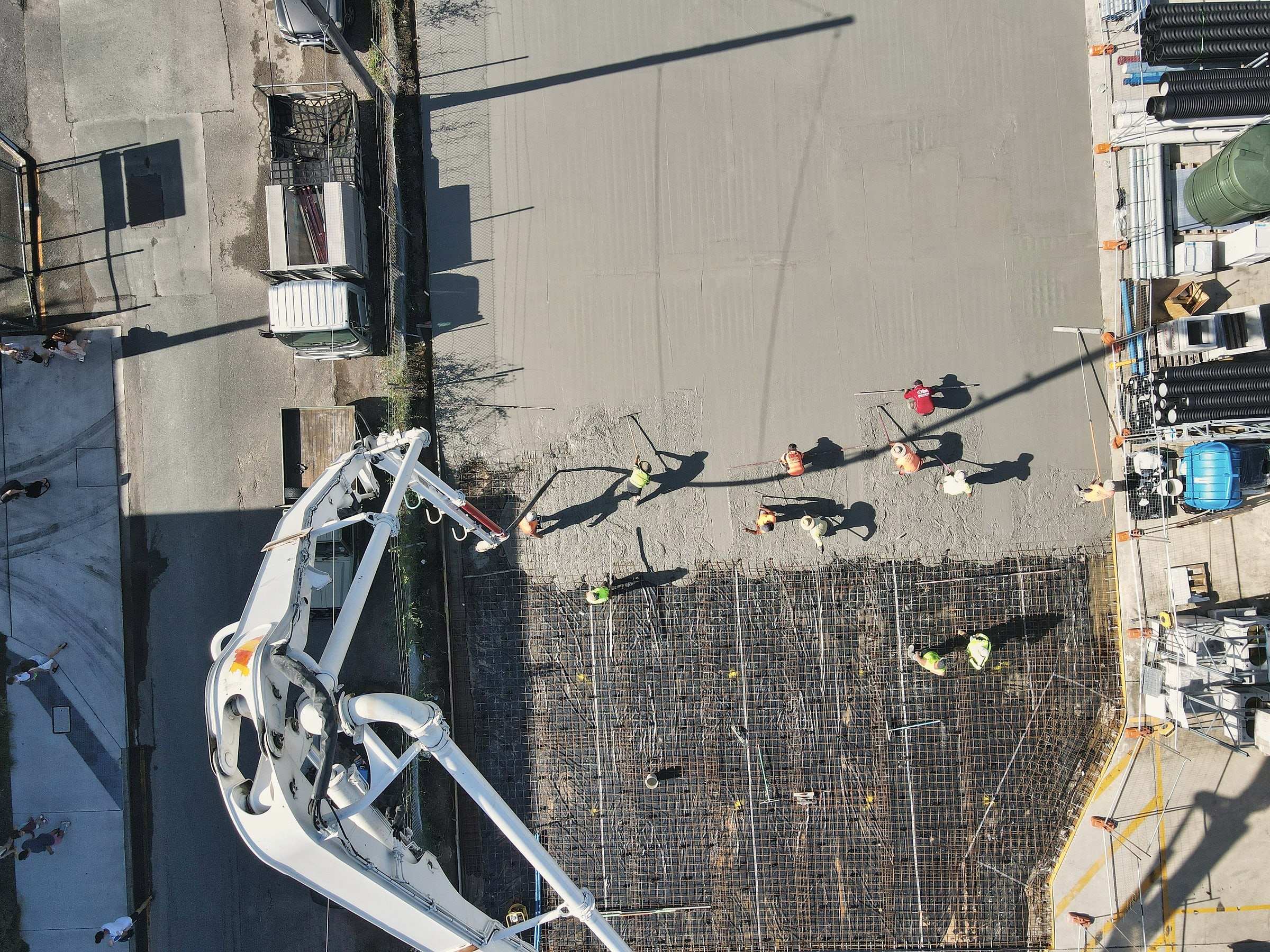 A concrete pour seen from above: the pump boom and a crew spreading concrete over steel reinforcing mesh