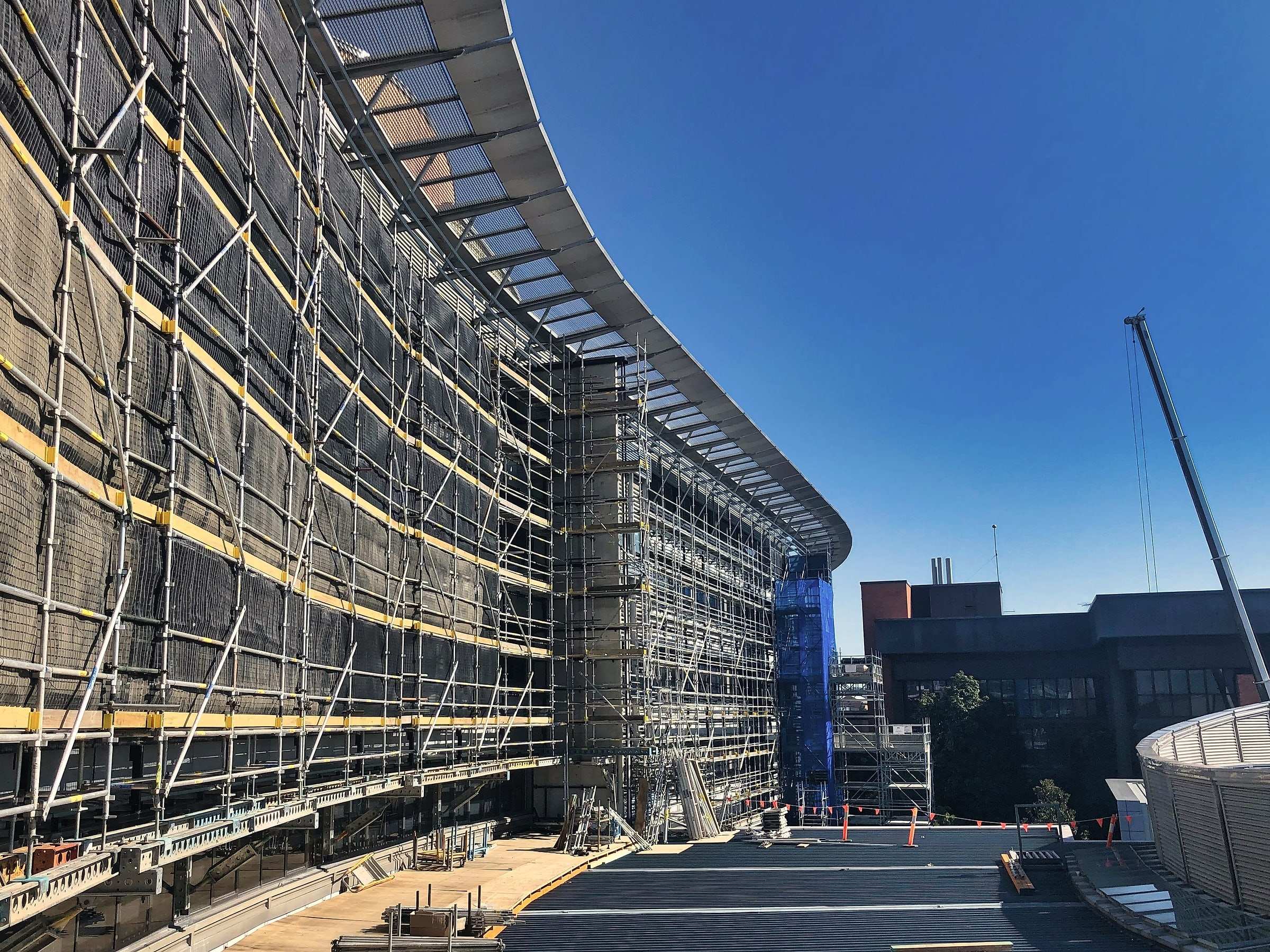 A long curved building facade wrapped in scaffold