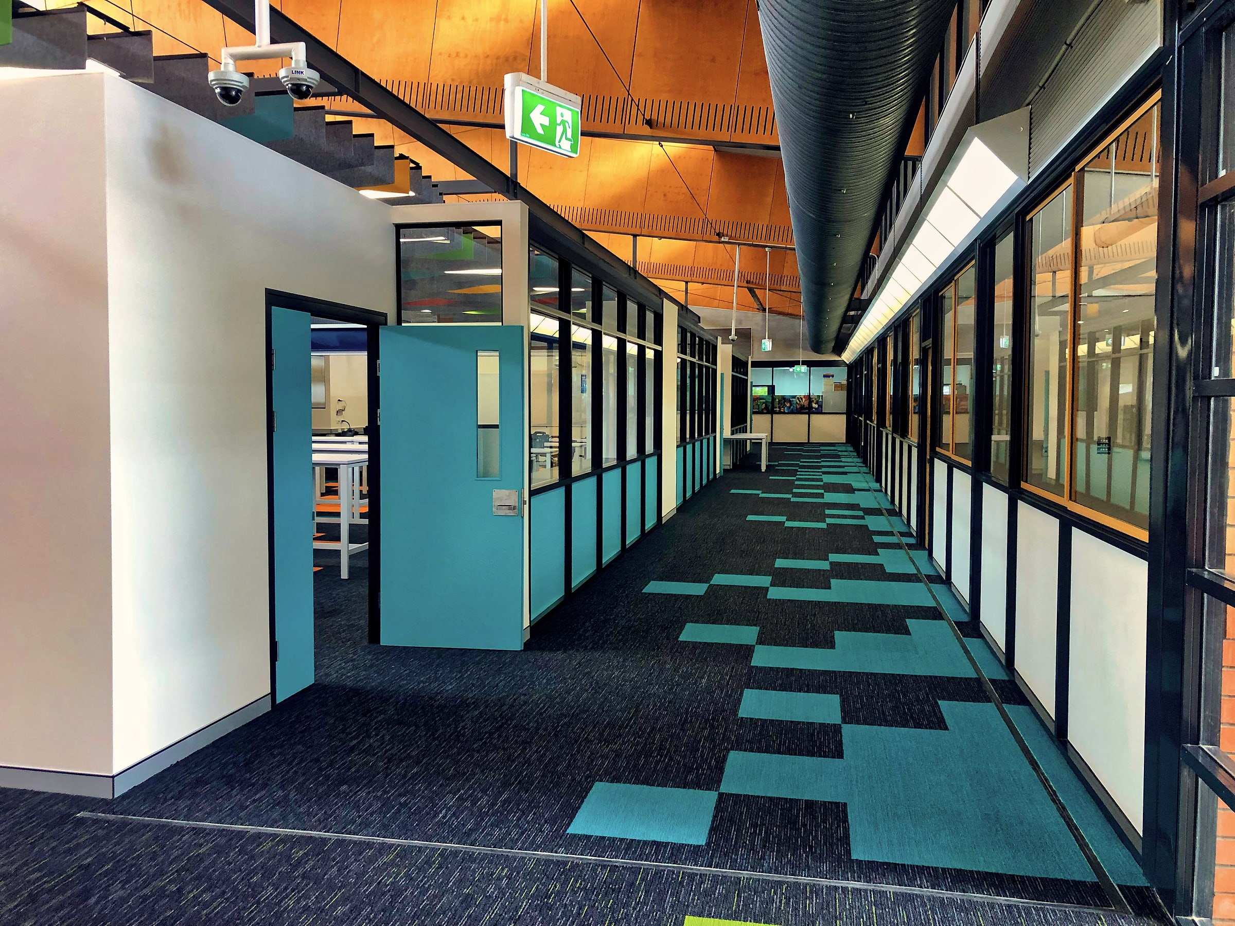 A newly finished school corridor with blue doors and patterned carpet